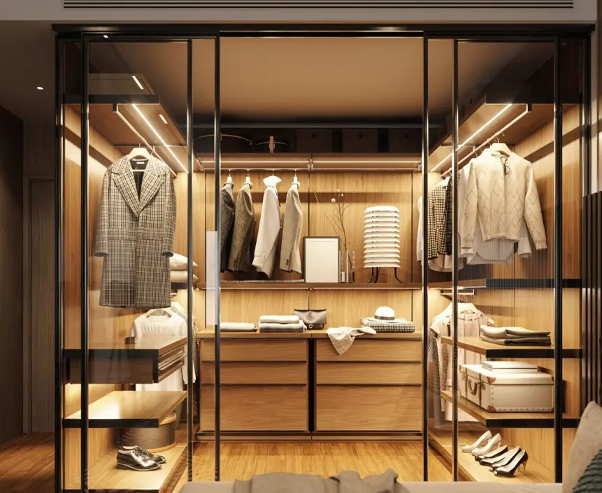 Luxurious clothing boutique display in a glass-walled cabinet with coats, shirts, and folded garments under warm lighting.
